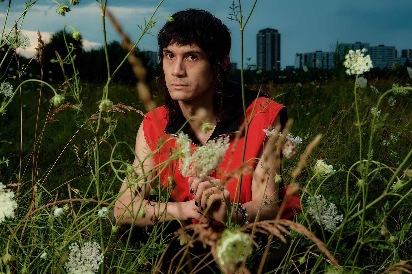 A colorful portrait of the artist Objekt with flowers in front of him and an urban cityscape in the background